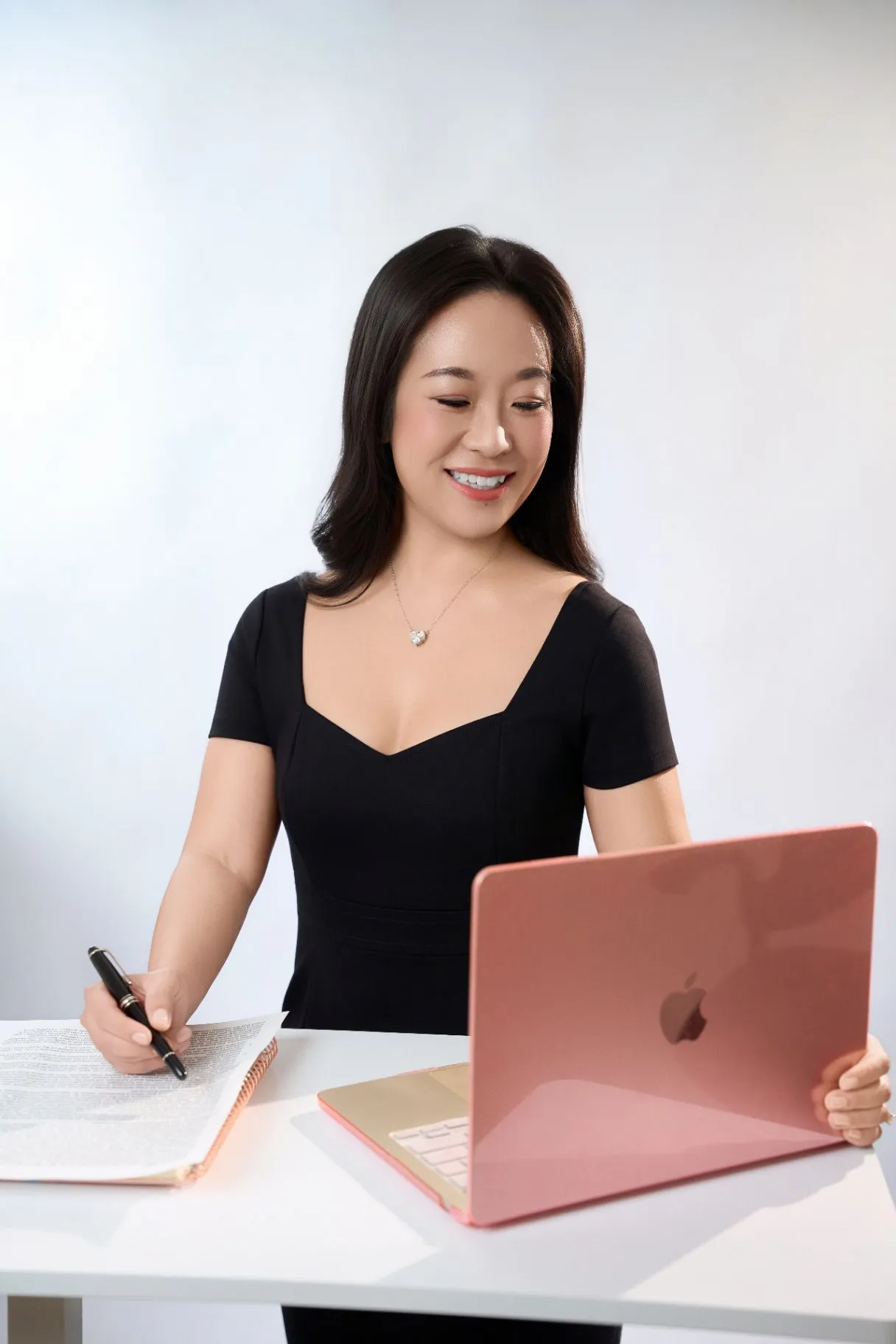 Dr. Nao J. Gamo smiling while writing in a notebook beside her laptop